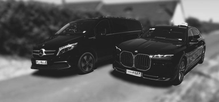 Deux voitures noires garées sur une route, l'une est un SUV, l'autre une berline.